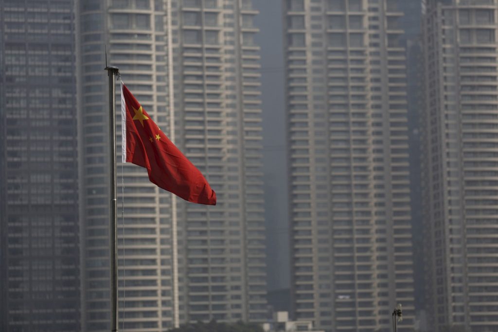 Bandeira da China, muitos prédios ao fundo. Existe uma bolha imobiliária na China? O que ela pode afetar nas suas importações? O Trade War influencia nessa bolha imobiliária?