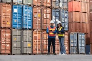 Trabalhadores inspecionam contêineres em um terminal, representando Regimes Aduaneiros Especiais.